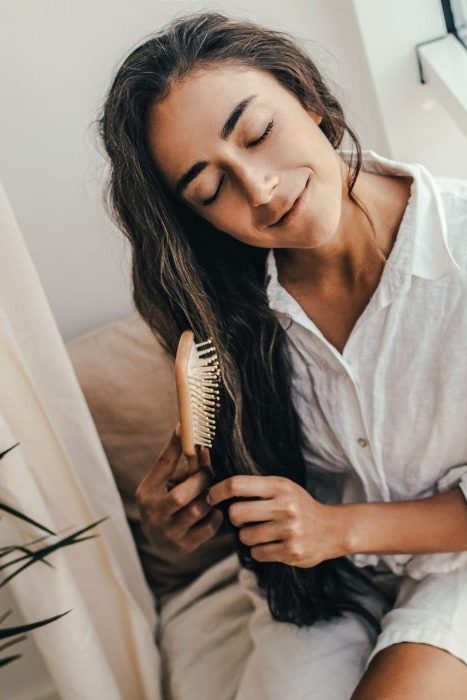 Young woman applying natural organic essential oil on hair and s Young woman applying natural organic essential oil on hair and skin. Home spa and beauty rituals. Skin care.
